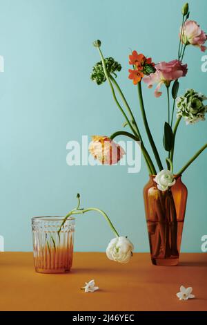 Vertikale Stillleben Komposition auf buntem Blumenstrauß in brauner Glasvase vor hellblaugrünem Wandhintergrund Stockfoto
