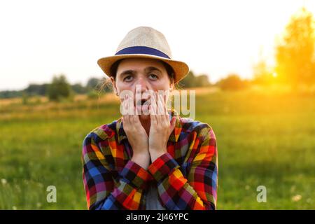 Unschärfe lustige junge Frau zeigt Augen und Hand und Blick auf die Kamera auf Natur Sonnenuntergang Hintergrund draußen. Nahaufnahme Porträt Mädchen Ausdruck, emoti Stockfoto