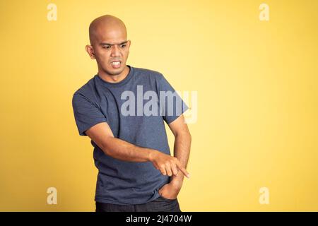 Wütender asiatischer Glatze zeigt im Stehen nach unten Stockfoto