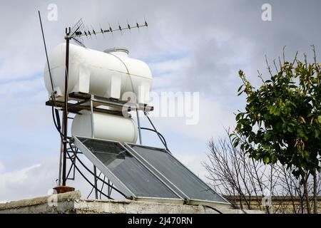 Solare Warmwasserbereitung mit großem Wasserbehälter und Kessel auf dem Dach des Hauses, auch analoge Fernsehantenne Stockfoto