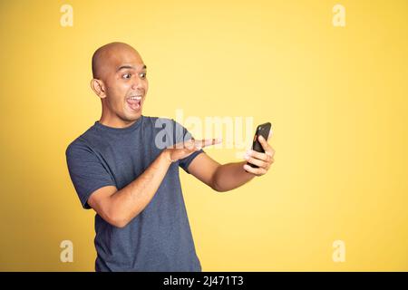 Aufgeregt asiatischen Mann machen Videoanruf mit einem Handy Stockfoto