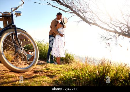 Sommer liebend. Aufnahme eines jungen Paares, das sich bei einem Date draußen in der Natur umarmt. Stockfoto