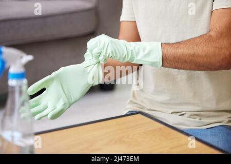 Ich muss meine Hände schützen. Aufnahme einer nicht erkennbaren Person, die zu Hause einen Tisch putzt. Stockfoto