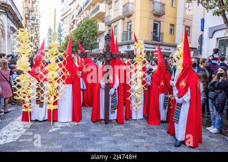 Huelva, Spanien - 10. April 2022: Nazarener und Büßer am Palmsonntag während der Karwoche in der Prozession La Borriquita mit Palmen aus Elche, Spa Stockfoto