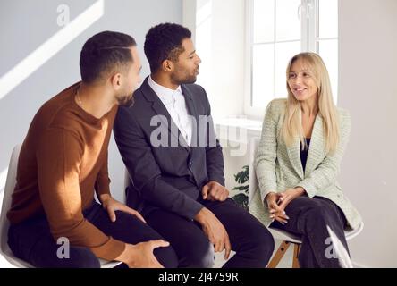 Kollegen unterhalten sich während eines informellen Treffens freundlich, tauschen Erfahrungen und Ideen aus. Stockfoto