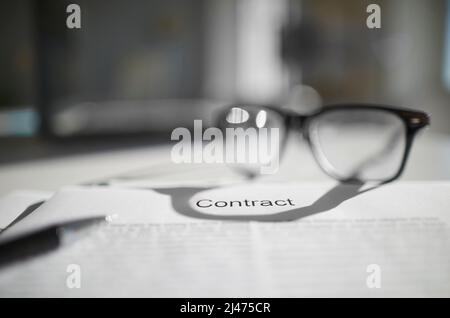 Ein Vertrag auf Arbeitstisch mit Brille und Bleistift. Die Dokumente sind zum Signieren bereit. Geschäftskonzept. Kooperationsvereinbarung. Stockfoto