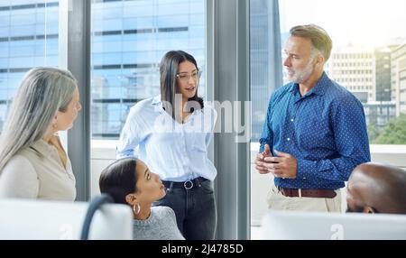 Sein Wissen und sein Fachwissen weitergeben. Eine kurze Aufnahme eines gutaussehenden, reifen Geschäftsmannes, der sich im Büro an seine Kollegen wendet. Stockfoto