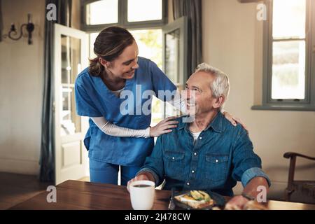 Nichts steigert meine Stimmung wie gutes Essen. Aufnahme einer jungen Krankenschwester, die während des Frühstücks in einem Pflegeheim einen älteren Mann aufgesucht hat. Stockfoto