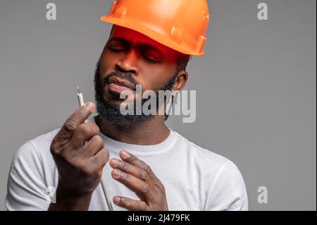 Arbeiter, der ein Netzkabel in der Hand untersucht Stockfoto
