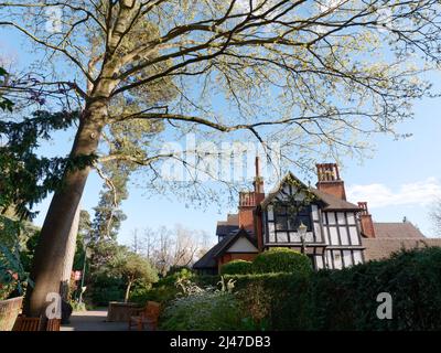 Watford, Hertfordshire, England, April 07 2022: Baum, Blumenbeete, Hecke und Bank auf dem Gelände von Bhaktivedanta Manor, einem ISKCON-Standort. Stockfoto