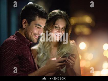 Das ist meine Nummer. Aufnahme eines jungen Paares, das nachts ihr Smartphone zusammen benutzt. Stockfoto