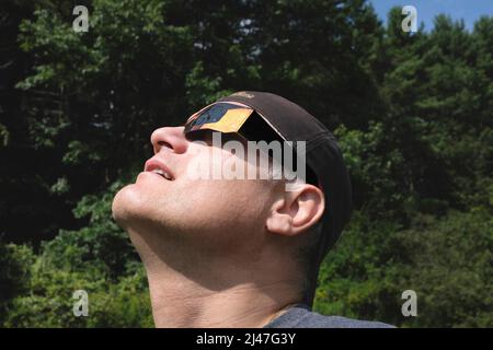 Mann mit mittleren Erwachsenen, der eine Eclipse-Brille trägt, während er die partielle Sonnenfinsternis betrachtet Stockfoto