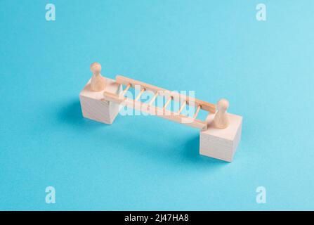 Zwei Menschen verbinden sich über eine Leiter, bauen eine Brücke zwischen Männern, Trennung und Verbindungskonzept, treffen sich, um Grenzen zu überwinden Stockfoto