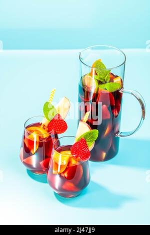 Gläser mit traditionellem Sangria-Cocktail, dekoriert mit Stücken frischer Erdbeere, einer Prise Minze und Stroh aus Öko-Papier. Stockfoto