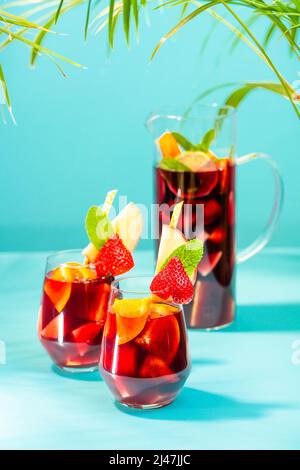 Gläser mit traditionellem Sangria-Cocktail, dekoriert mit Stücken frischer Erdbeere, einer Prise Minze und Stroh aus Öko-Papier. Stockfoto