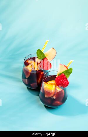 Gläser mit traditionellem Sangria-Cocktail, dekoriert mit Stücken frischer Erdbeere, einer Prise Minze und Stroh aus Öko-Papier. Stockfoto