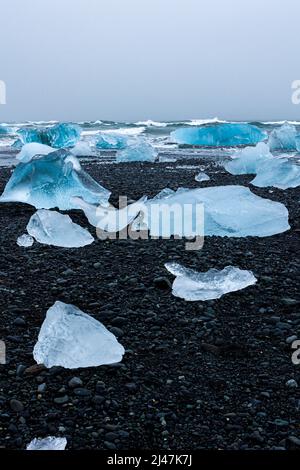 Wunderschöne blaue Eisberge und Eisbrocken an einem vulkanischen schwarzen Sandstrand (Diamond Beach, Island) Stockfoto