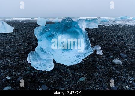 Wunderschöne blaue Eisberge und Eisbrocken an einem vulkanischen schwarzen Sandstrand (Diamond Beach, Island) Stockfoto