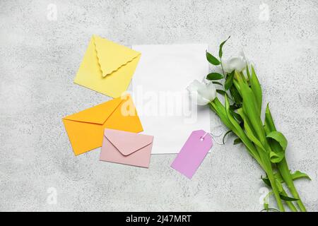 Umschläge mit leerer Karte und schönen Blumen auf hellem Hintergrund Stockfoto