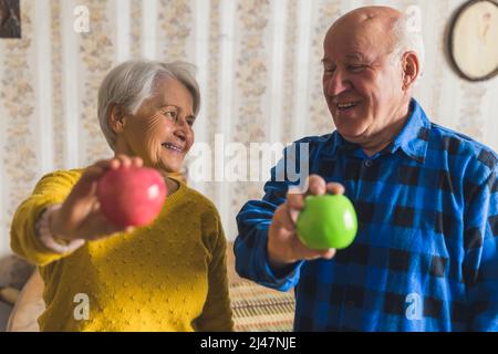 Glückliches Seniorenpaar hält Äpfel gesund Lebensstil Konzept Medium closeup Wohnzimmer. Hochwertige Fotos Stockfoto
