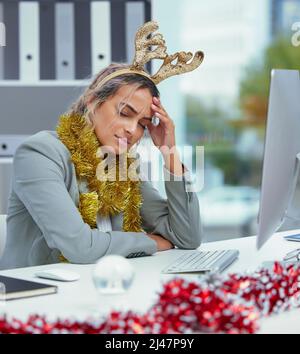 Mit einer Migräne kann man nicht streiten. Aufnahme einer jungen Frau, die an ihrem Schreibtisch im Büro unter starken Kopfschmerzen leidet. Stockfoto