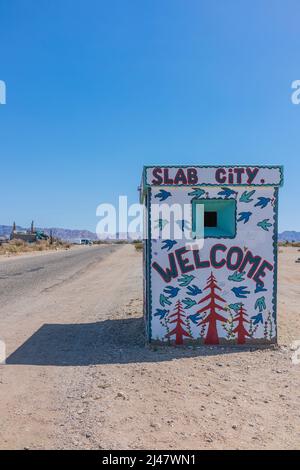 Ein winziges Gebäude mit einem Wandgemälde, das Besucher in Slab City willkommen heißt. Es ist eine netzunabhängige Gemeinde ohne kommunale Dienste. Es bekommt es nam Stockfoto