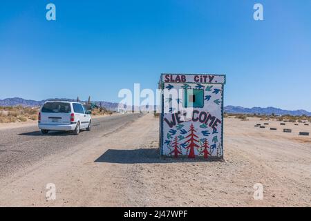 Ein winziges Gebäude mit einem Wandgemälde, das Besucher in Slab City willkommen heißt. Es ist eine netzunabhängige Gemeinde ohne kommunale Dienste. Es bekommt es nam Stockfoto