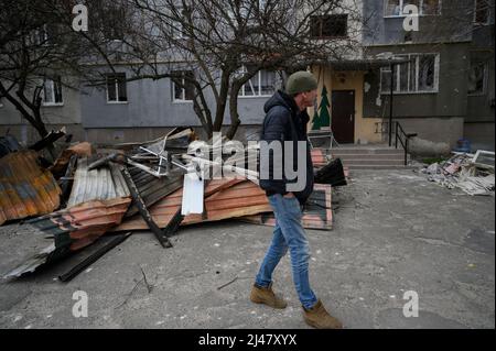 Makariv, Kiew, Ukraine. 12. April 2022. Ein Mann sah zwischen den Überresten der Dächer spazieren gehen. Das Dorf Makariv, westlich von Kiew, zeigt offensichtliche Anzeichen von Schäden während der russischen Besatzung, dauerte bis Ende März 2022. Die Bewohner versuchen, mit grundlegenden Reparaturen und Kontrollen mit der Situation fertig zu werden. (Bild: © Valeria Ferraro/ZUMA Press Wire) Stockfoto