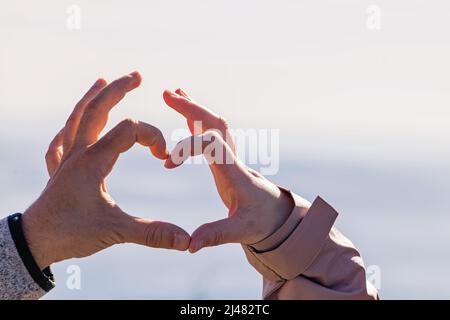Mann und Frau halten ihre Hände in einer herzförmigen Nahaufnahme zusammen Stockfoto