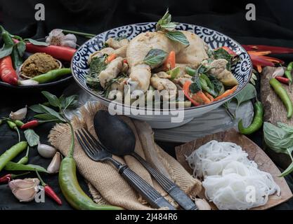 Grünes Kerrys mit Hühnchen und grün-weißen Sorten thailändischer Auberginen (Kaeng Khiao wan) in einer Keramikschale serviert mit thailändischen Reisnudeln (fermentierter Reis f Stockfoto