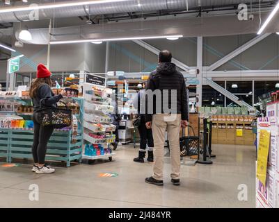 Kirkland, WA USA - ca. April 2022: Blick auf Männer und Frauen, die sich für die Selbstabholkiosks in einem Whole Foods-Supermarkt anstellen. Stockfoto