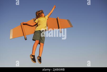 Kids Leader und Gewinner, Erfolg beginnt. Junge Pilot fliegen gegen einen blauen Himmel. Aufgeregt Kind Junge spielen mit Spielzeug Jetpack Flügel Superheld im Park. Stockfoto