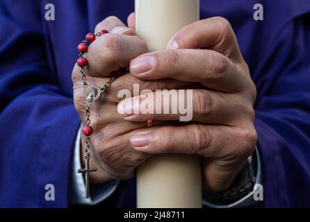 Caus, Spanien. 13. April 2022. Ein Büßer hält während einer Prozession eine Kerze und einen Rosenkranz in der Hand, während sie den Heiligen Dienstag feiern. Nach zwei Jahren der Reisebeschränkungen und -Annullierungen in Covid-19 in Spanien konnte das Unternehmen seine Aktivitäten zur Feier der Karwoche wieder aufnehmen. Kredit: SOPA Images Limited/Alamy Live Nachrichten Stockfoto