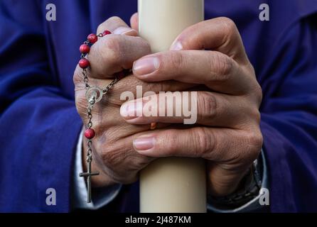 Caus, Spanien. 13. April 2022. Ein Büßer hält während einer Prozession eine Kerze und einen Rosenkranz in der Hand, während sie den Heiligen Dienstag feiern. Nach zwei Jahren der Reisebeschränkungen und -Annullierungen in Covid-19 in Spanien konnte das Unternehmen seine Aktivitäten zur Feier der Karwoche wieder aufnehmen. (Foto von Miguel Candela/SOPA Images/Sipa USA) Quelle: SIPA USA/Alamy Live News Stockfoto