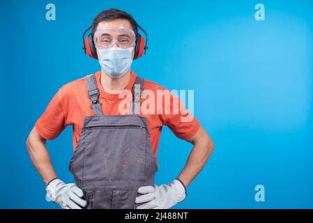 Positiver Handwerker in Gesichtsmaske während der Arbeit Stockfoto