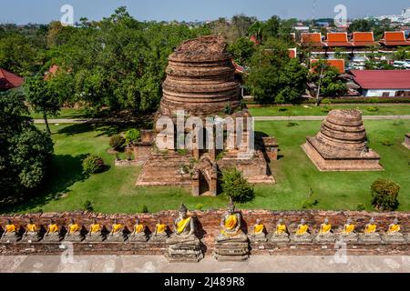 Eine hohe Ansicht einer der Ruinen hinter einer Ziegelmauer mit einer Reihe von buddha-Statuen. Stockfoto