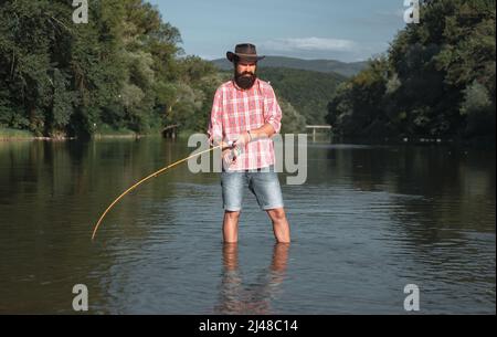 Mann Fischer fängt einen Fisch. Fliegenfischen. Die Bachforelle wird im Fischernetz gefangen. American Angler Angeln. Forellenfisch. Fischer. Stockfoto