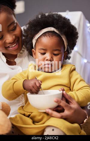 Mama macht das beste Essen. Aufnahme eines kleinen Mädchens, das mit ihrer Mutter zu Hause frühstückte. Stockfoto