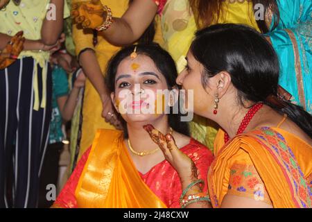 Indische Hindu-Braut mit Kurkuma-Paste auf ihr Gesicht aufgetragen und Spaß mit ihrer Familie und ihren Freunden. Indisches Hochzeitskonzept Stockfoto