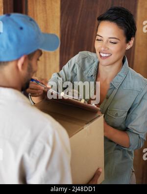 Schneller und freundlicher Service. Aufnahme einer jungen Frau, die vor ihrer Haustür stand und ein Paket von einem Kurier unterschrieb. Stockfoto