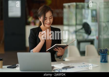 Schöne asiatische Geschäftsfrau, die sich das pädagogische Webinar auf einem Laptop ansieht. Finanzierungskonzept. Stockfoto