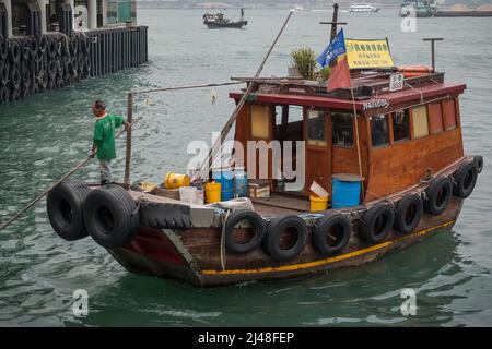 Ein kleiner traditioneller Müll wird verwendet, um schwimmenden Müll aus Victoria Harbour in der Nähe der Central Ferry Piers, Hong Kong, 2007, zu entfernen Stockfoto