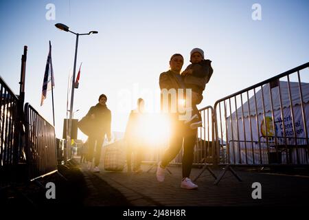 Przemysl, Polen. 13. April 2022. Eine Familie, die aus der Ukraine geflohen ist, geht am Morgen zu einem Bus am Grenzübergang Medyka auf der polnischen Seite, direkt über die ukrainische Grenze. Quelle: Christoph Soeder/dpa/Alamy Live News Stockfoto