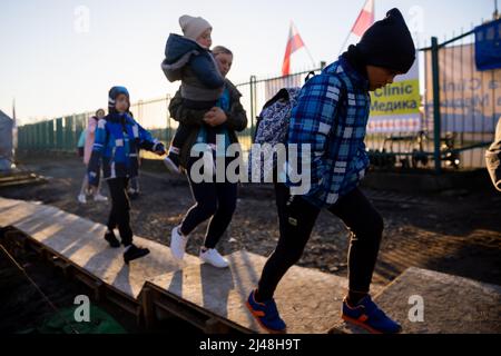 Przemysl, Polen. 13. April 2022. Eine aus der Ukraine geflohene Familie macht sich auf die Weiterreise mit dem Bus am Grenzübergang Medyka auf polnischer Seite kurz über der ukrainischen Grenze auf den Weg. Quelle: Christoph Soeder/dpa/Alamy Live News Stockfoto