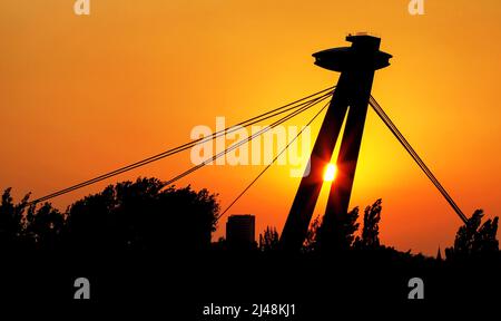 Sonnenschein und farbenfroher Sonnenaufgang durch die Silhouette der SNP-Brücke in der Stadt Bratislava, Slowakei Stockfoto