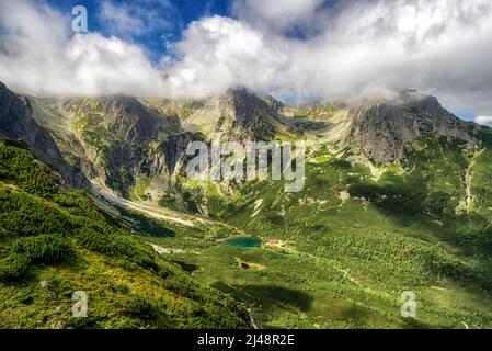 Tarn Zelene pleso in der Hohen Tatra in der Slowakei. Alpine Sommerberglandschaft mit Wolken über Hügeln Stockfoto