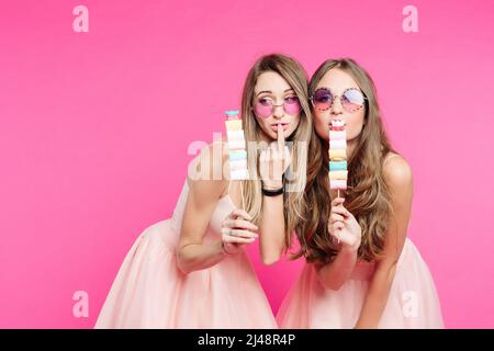 Schöne Mädchen in rosa wie Prinzen zeigen Marshallows auf Stock. Stockfoto