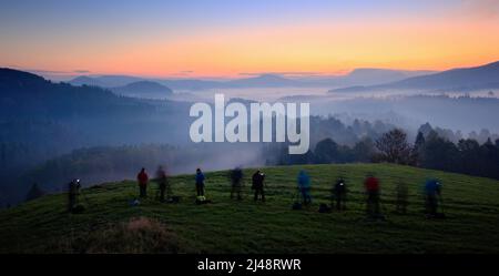 Workshop Landschaftsfotografie. Fotografen während des Sonnenaufgangs am Berg auf Kurs. Hügel und Dörfer mit nebligen Morgen. Nebel in Tschechien, Herbst Stockfoto