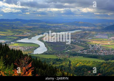 Zilina Stadt im Herbst von Mala Fatra Berg. Blick auf die Abendstadt aus den Bergen in der Slowakei, dunkelgraue Sturmwolken. Bergwald, Vah Stockfoto