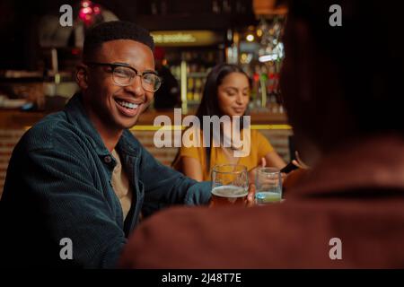afroamerikanischer Mann lächelt, während er Zeit mit Freunden im Restaurant genießt Stockfoto